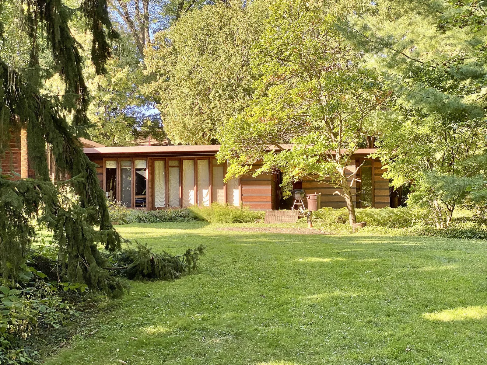 The first Jacobs House in Madison: a low brick and horizontal-wood house behind a deep lawn, glass along the garden side