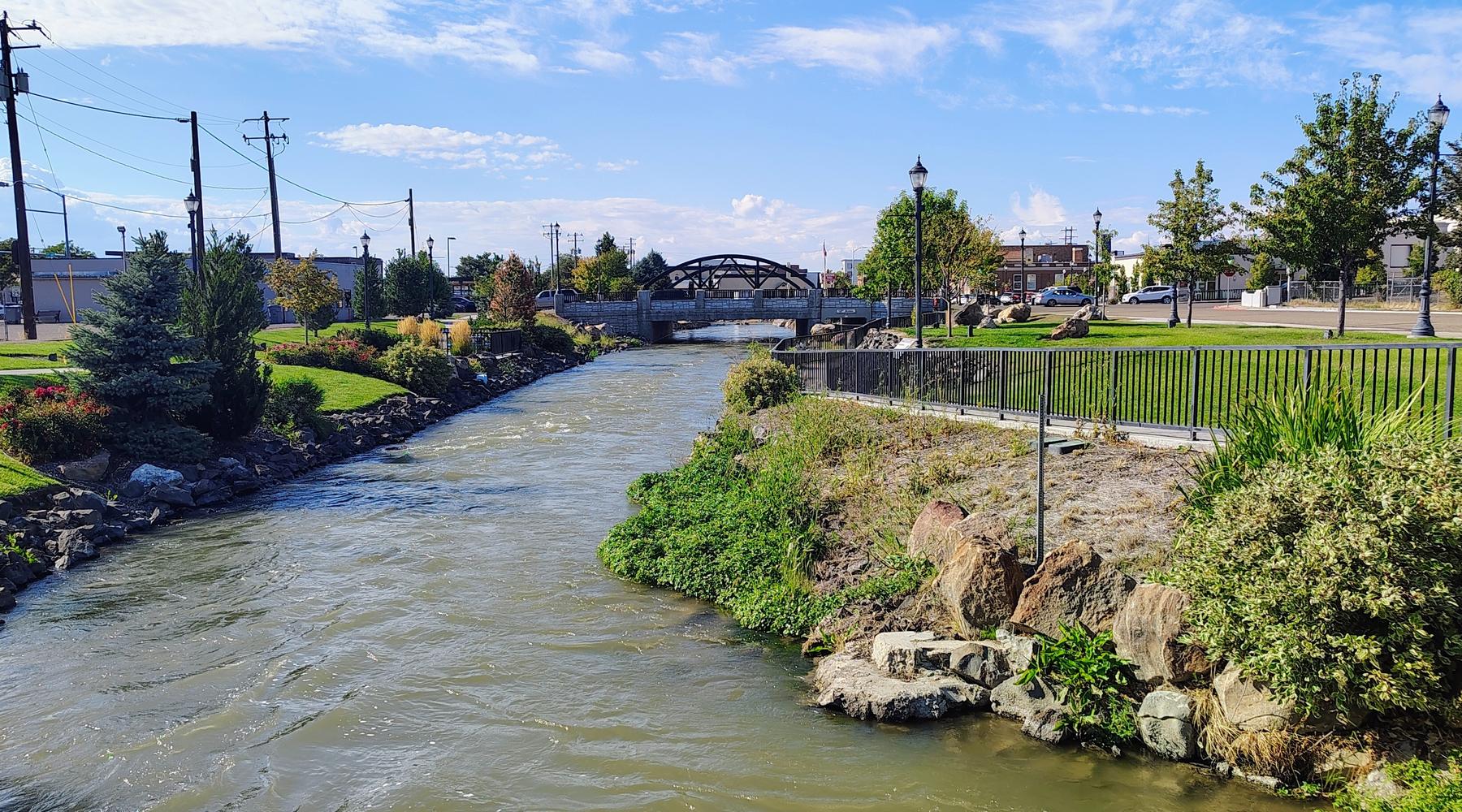 Indian Creek running through downtown Caldwell, with the arched footbridge and planted banks